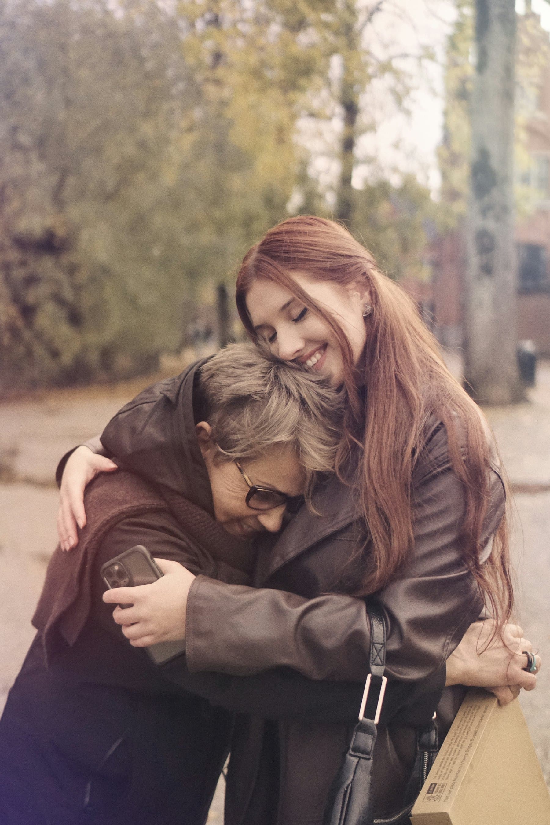 Two women sharing a warm, supportive hug on a city street