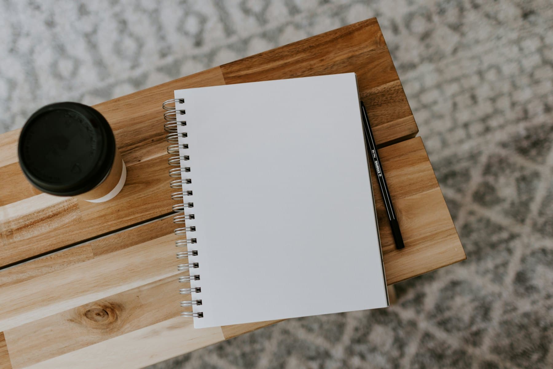 A notebook, pen and coffee on a table, ready for planning